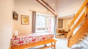 A room with a wooden bench, a table with a checkered tablecloth, a window with curtains, a wooden staircase, and a framed picture on the wall. - 280m from resort center, 1st floor, balcony, parking, tv, 47m², La Norma (La Norma)