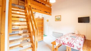 A room with a wooden staircase, a table with a patterned tablecloth, and a television on the wall. - 280m from resort center, 1st floor, balcony, parking, tv, 47m², La Norma (La Norma)