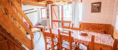 A wooden dining area with a table set for four, surrounded by wooden chairs.