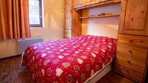 Camera da letto con un letto, un'armadio in legno e una finestra con tende.