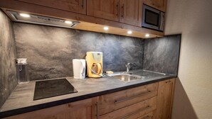 Una cucina con forno a microonde, macchina del caffè e bollitore sul piano di lavoro.