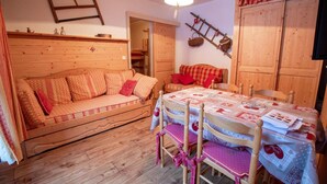 Una stanza accogliente con un divano di legno, un tavolo da pranzo con sedie e un pavimento in legno.