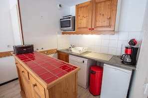 Eine kleine Küche mit Holzschränken, einem Toaster, einer Kaffeemaschine und einem Geschirrspüler.