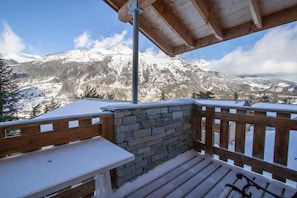 A wooden deck with a stone wall, overlooking a snowy mountain landscape. - Chalet, 300m from resort center, Ground floor, balcony, parking, tv, ski locker, 45m², La Norma (La Norma)