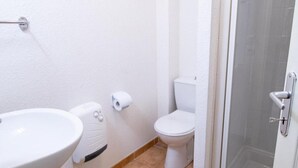 Une salle de bain avec un lavabo, des toilettes et une douche, le tout de couleur blanche.