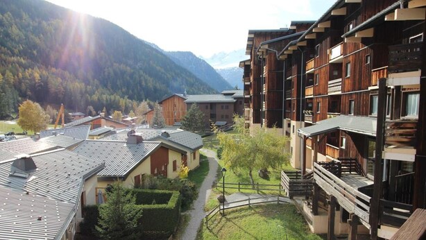 A residential area with wooden buildings, a pathway, and a mountain backdrop. - 130m from ski slopes, 3rd floor, balcony, parking, tv, ski locker, 35m², La Norma (La Norma)