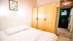Ein Schlafzimmer mit einem Bett, einem Holzschrank und einem gerahmten Bild an der Wand.