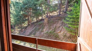 Eine Holzblockhütte mit einem Balkon mit Blick auf einen bewaldeten Hang.