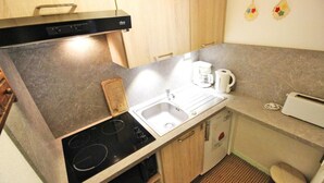 Eine kleine Küche mit Einbauherd, Spüle und Toaster.