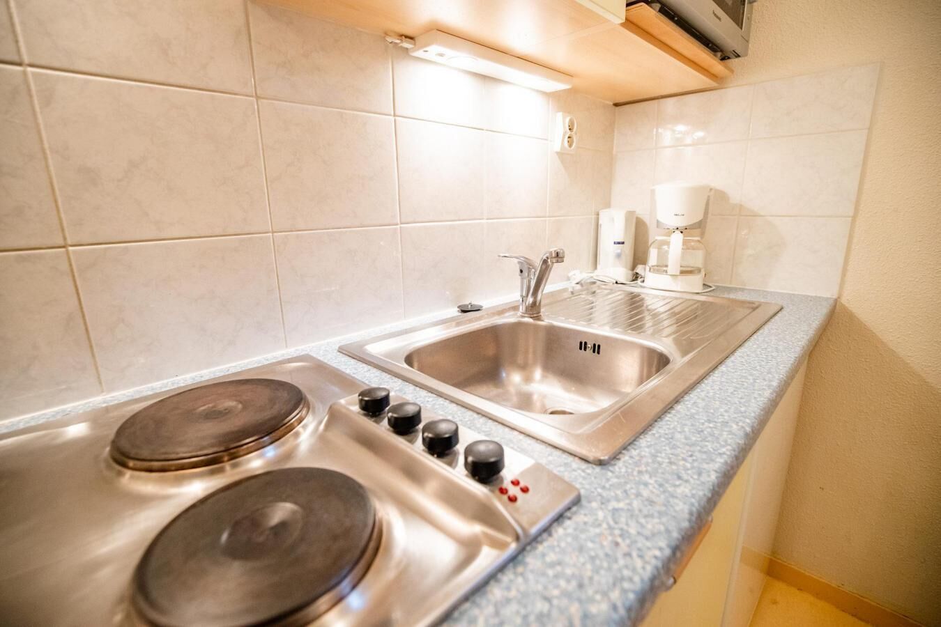 A modern kitchen with a gas stove, stainless steel sink, and a coffee machine.