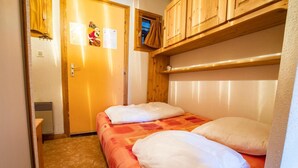 Una habitación pequeña y acogedora con una cama individual, cabecera de madera y un ventanal.