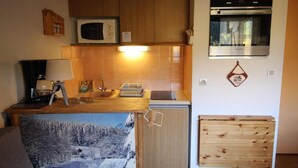 Una cocina compacta con microondas, horno y un refrigerador pequeño.