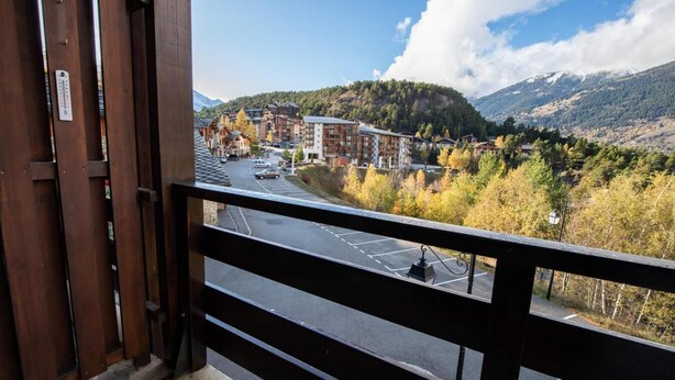 En balkon med udsigt over en by, bygninger og et bjerglandskab.