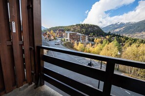 Un balcon offrant une vue sur une ville, des bâtiments et une chaîne de montagnes.