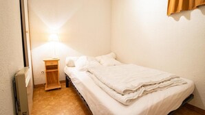 Et lille, rent værelse med en enkelt seng, et natbord og en lampe.