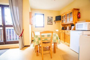 Cozy dining area with a table set for four, refrigerator, and microwave.