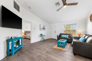 A modern living room with a flat-screen TV, a ceiling fan, a sofa, and a coffee table.