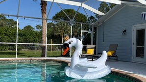 A swimming pool with a swan float, a covered patio, and outdoor furniture. - Sunny House with heated pool, 12min drive to Engelwood Beach, Port Charlotte FL (Port Charlotte)
