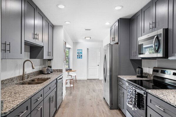 A modern kitchen with granite countertops, stainless steel appliances, and dark gray cabinetry.