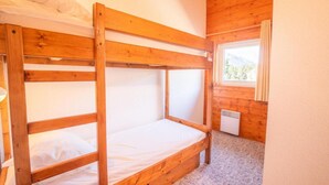 A bunk bed room with wooden walls and a window with curtains. - 100m from ski slopes, 2nd floor, balcony, parking, tv, 54m², La Norma (La Norma)