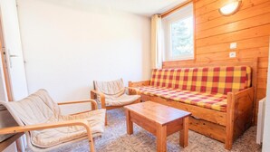 A cozy room with a wooden sofa, two chairs, and a small table. - 100m from ski slopes, 2nd floor, balcony, parking, tv, 54m², La Norma (La Norma)