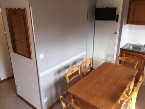 A compact kitchen with a wooden table and chairs, a refrigerator, and a microwave. - 280m from resort center, 2nd floor, balcony, parking, tv, 47m², La Norma (La Norma)