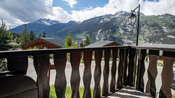 Ein Holzbalkon mit Blick auf Berge und eine Holzhütte.