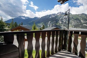 Un balcón de madera con vistas a montañas y una cabaña de madera.