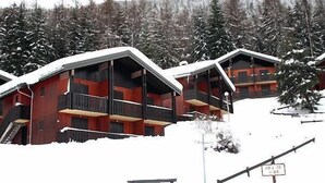 Eine Reihe von Holzhütten mit Balkonen, umgeben von schneebedeckten Bäumen.