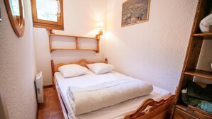 Ein kleines, gemütliches Schlafzimmer mit einem hölzernen Bett, einer Nachttischlampe und einem gerahmten Bild an der Wand.