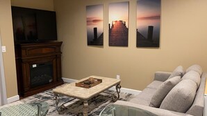 Una sala de estar con chimenea, televisor y tres cuadros en la pared.