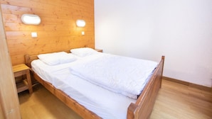 Un lit en bois avec une literie blanche, dans une pièce aux murs et au plancher en bois.