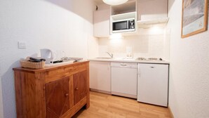 Une cuisine compacte équipée d’un meuble en bois, d’un four à micro-ondes, d’un évier et d’un lave-vaisselle.
