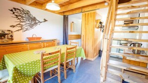 Un interior de madera con una mesa de comedor y sillas, una escalera y un estante en la pared.
