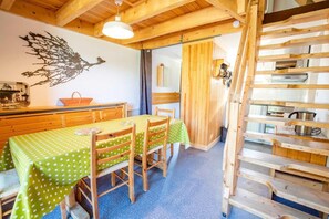 Un interior de madera con una mesa de comedor y sillas, una escalera y un estante en la pared.