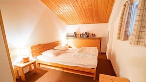 Un dormitorio con cama de madera, una mesita de noche y una ventana con cortinas.