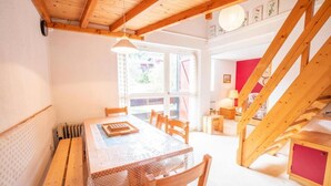 A dining area with a wooden table and chairs, a window with curtains, and a staircase with a red accent. - 280m from resort center, 1st floor, balcony, parking, tv, 54m², La Norma (La Norma)