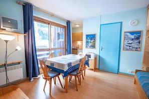 Cozy dining area with a table for four, television, and comfortable seating.