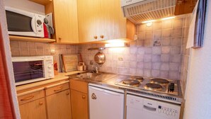 Eine kleine Küche mit Holzausstattung, einer Mikrowelle, einem Toaster, einem Spülbecken und einem Geschirrspüler von Bosch.