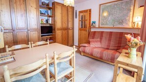 Ein gemütliches Zimmer mit einem Holzespeisetisch, Stühlen, einer Couch und einem Fernseher.