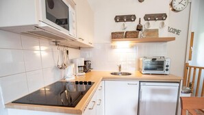 A compact kitchen with a stove, microwave, toaster, and sink.