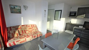 A compact living space with a sofa, dining table, chairs, a kitchenette, and a small window. - 300m from ski slopes, 1st floor, balcony, parking, tv, ski locker, 35m², La Norma (Villarodin-Bourget)