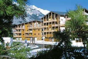 Un edificio de madera de varios pisos con balcones, con una imponente montaña nevada al fondo.