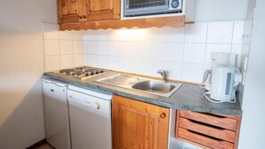 Uma cozinha compacta com micro-ondas embutido, fogão a gás, pia e máquina de café.