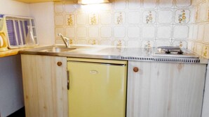 A compact kitchen with wooden cabinets, a yellow refrigerator, a microwave, and a sink. - 130m from ski slopes, 5th floor, balcony, parking, tv, ski locker, 35m², La Norma (La Norma)