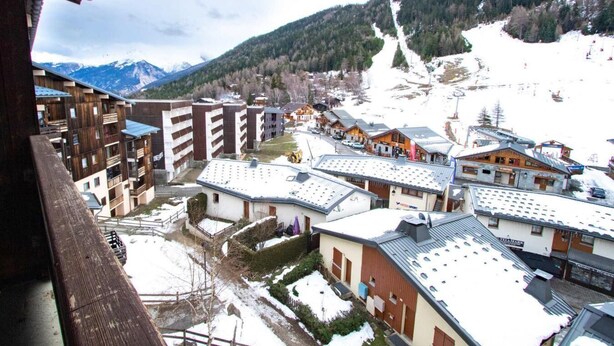 A snow-covered mountain town with buildings, including a hotel with a ski slope in the background. - 130m from ski slopes, 5th floor, balcony, parking, tv, ski locker, 35m², La Norma (La Norma)