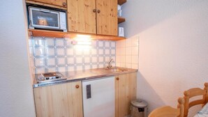 A compact kitchen with wooden cabinets, a small sink, and a refrigerator.