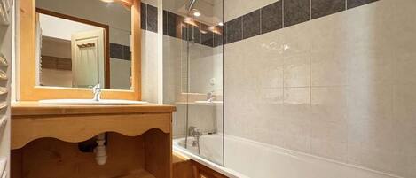 Une salle de bain avec un meuble-lavabo en bois, une cabine de douche en verre et une baignoire.