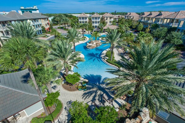 Un resort con piscina central, palmeras y edificios de varios pisos.