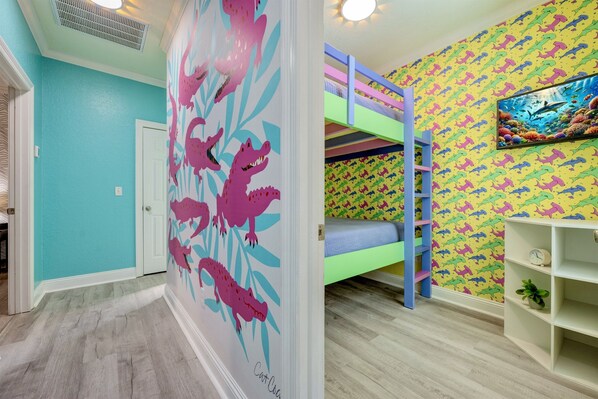 A child's room with a bunk bed, a wall with dinosaur patterns, and a shelf with a clock and plant. - Walk2Beach | Golf Cart | Arcades | Dog Friendly | Stocked Kitchen (Destin)